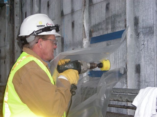 100N Demo 109N Roof
Worker cuts a 3"  'coupon' from the side of a ventilation duct.  Encapsulant is sprayed into the duct to lock down rad material using holes such as this.
