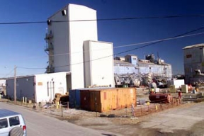 The Bio-Dentrification Tower and Plants 2 and 3 Prior to Demolition.
Plants 2 and 3, the Ore Refinery Plants, were used to convert feed materials and recycled scrap to high purity uranium trioxide (UO3). Three processes were used during the conversion: digestion, where uranium was converted to soluble uranyl nitrate; extraction, where uranyl nitrate was extracted by a solvent mixture; and denitration, where high purity uranyl nitrate was converted to UO3. The D&D of the plants consists of surface decontamination, building and equipment dismantlement, size reduction of building material and the loading of demolition debris into rolloff boxes for transfer to the On-Site Disposal Facility. 
Keywords: Fernald Closure Project Fernald Green Salt Plant, Feed Materials Production Center, Fernald, Ohio (FEMP)