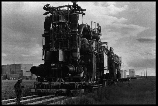 Nuclear-Powered Jet Airplane Engines (1957-1961)
In front of the technician with a Geiger counter stands a vertical nuclear reactor made into a jet airplane engine. Behind it is a second, horizontal reactor engine. Nuclear-powered jet airplanes were intended to carry nuclear bombs and fly a pattern around the Soviet Union. The program was rendered obsolete by long-range missile technology. These are the only two nuclear jet airplane engines in existence. Idaho National Engineering Laboratory, Idaho Falls, Idaho. November 9, 1984. 
Keywords: Idaho National Engineering Laboratory, Idaho Falls, Idaho INEL