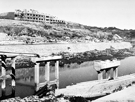 The destruction across the Urakami river valley
The Chinzei school from the east bank of the Urakami River. Although it appears that the building is intact, the entire roof had caved in.

The city did not suffer from a firestorm as had Hiroshima. However, the blast effects were more destructive, because of the bowl-shaped topography and the greater yield of the bomb.
