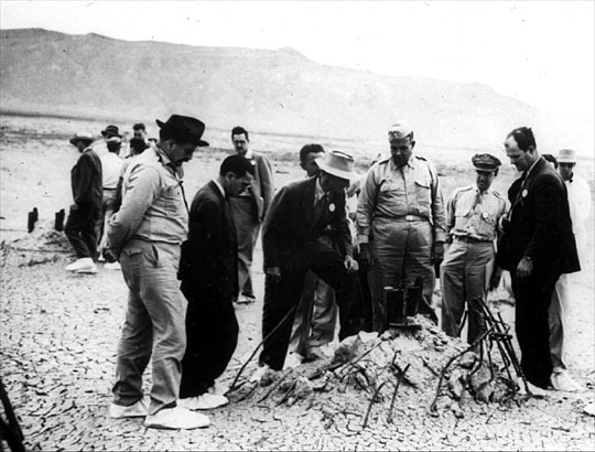 At the Trinity Test Site
In September 1945, many particpants returned to the Trinity Test site for news crews. Here Oppenheimer and Groves examine the remains of one the bases of the steel test tower.
