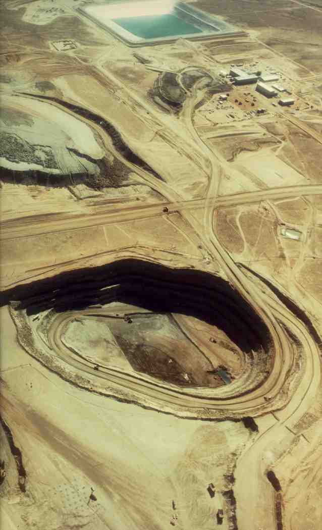 This aerial photograph of the Sweetwater Pit was taken on September 25, 1980. The lower portion of the photograph shows haul trucks. The overburden pile is shown in the center of the photograph. The photograph shows the overburden pile and haulage roads typical of an open pit uranium mine.
