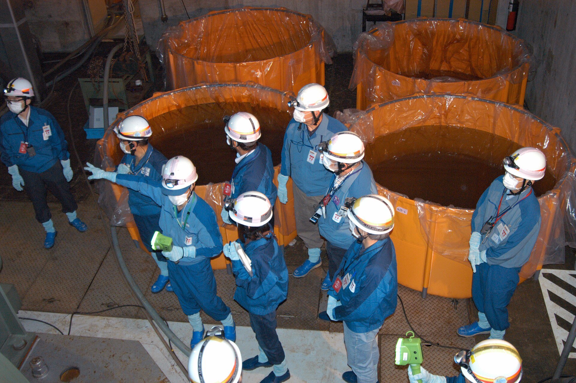 Fukushima Daini workers in hard hats by cylinders