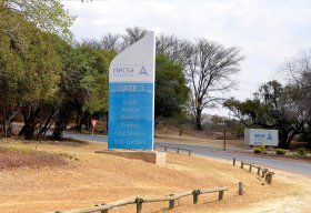 Pelindaba gate sign beside a tree-lined road